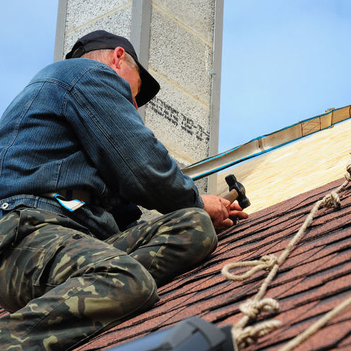 roofing contractor. roofing construction and building new house with modular chimney, skylights, attic exterior. roofers install, repair asphalt shingles or bitumen tiles on the rooftop outdoor
