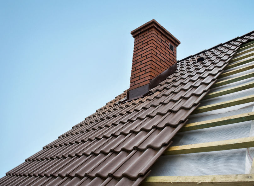 Roof under constructions with lots of tile and red brick chimney